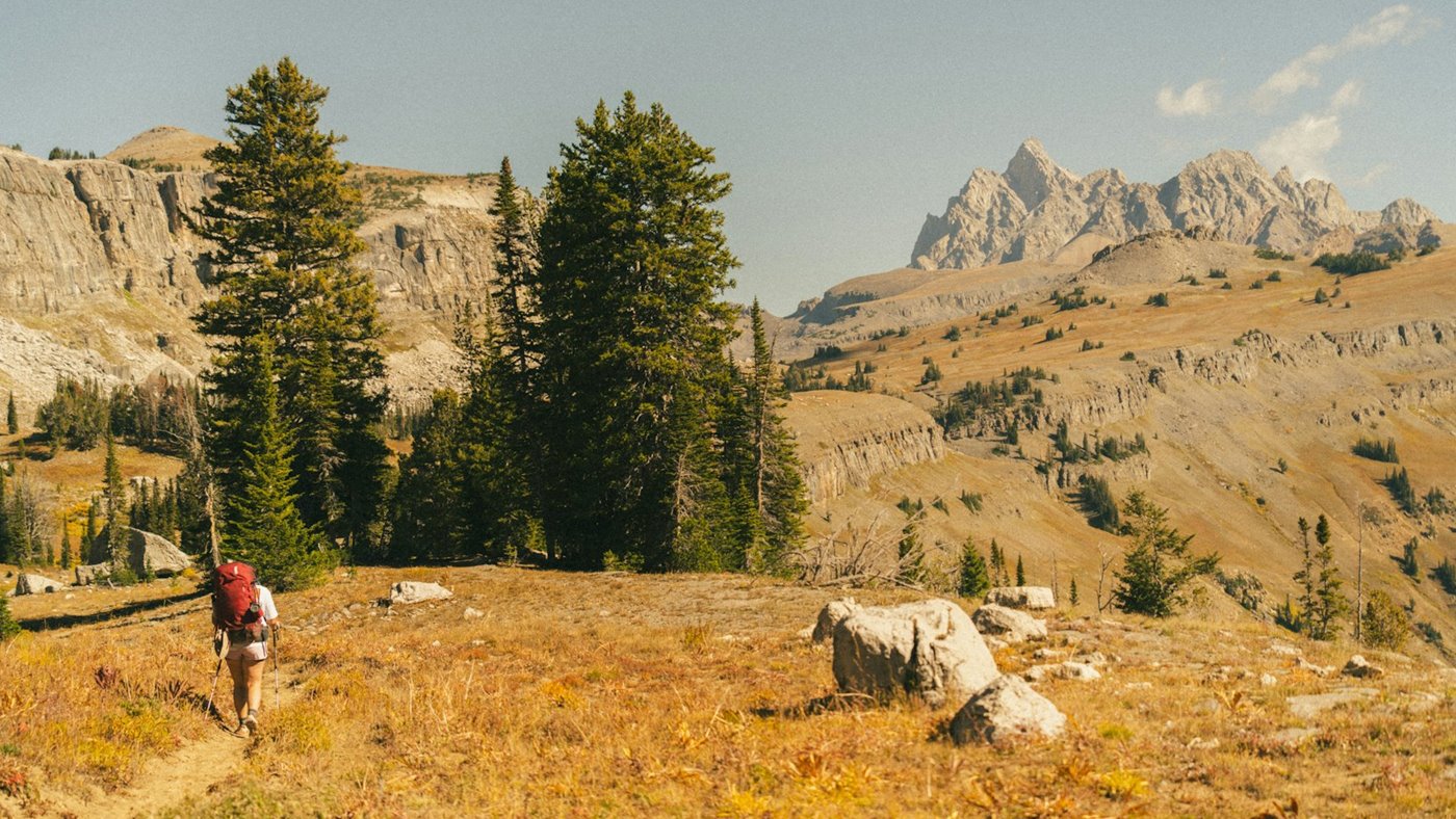 Hiker carrying a day pack on a mountain trail in open country