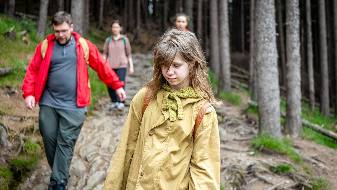 Family walking together on a forest trail with day packs