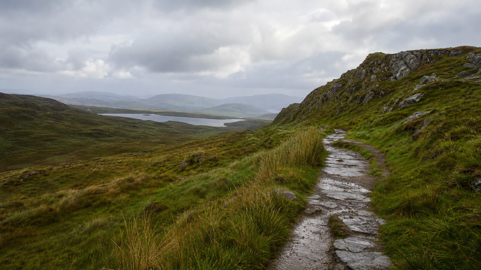 Winding footpath through open moorland and low hills after rain